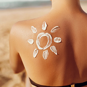 Sonne aus Sonnenmilch auf Rücken einer Frau