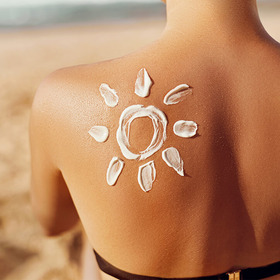 Sonne aus Sonnenmilch auf Rücken einer Frau