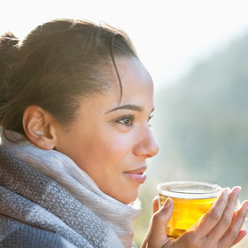 Eine Frau trinkt einen Tee mit Zitrone, um ihr Immunsystem mit Vitamin C zu stärken.