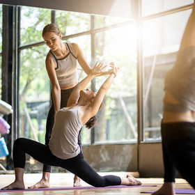 Yoga Trainerin korrigiert Haltung
