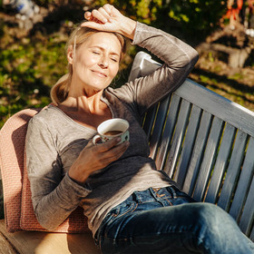 Eine Frau liegt auf einer Bank in der Sonne und tankt Vitamin D für ein starkes Immunsystem.