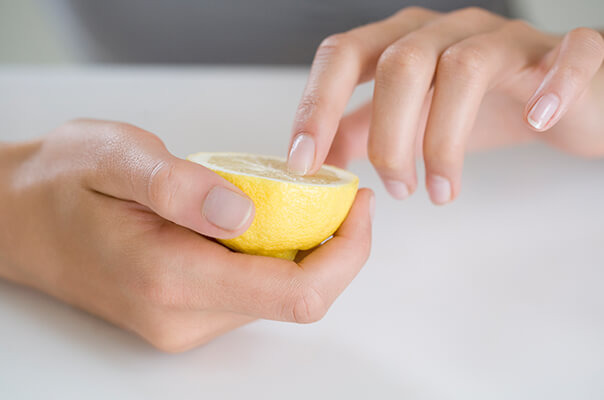 Frau pflegt Nägel mit Zitrone