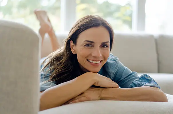 Lächelnde Frau liegt auf Sofa